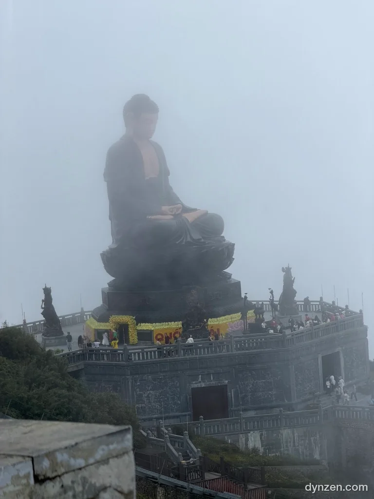 안개 속에 앉아 있는 거대한 불상과 그 아래 돌 기단