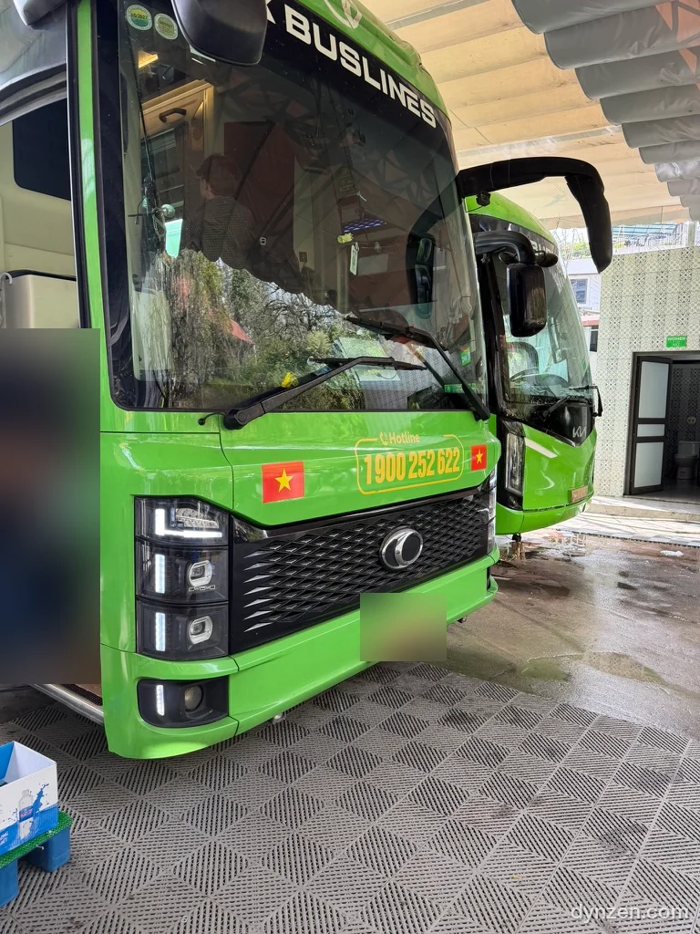 오피스 지붕 아래 서 있는 연두색 HK BUSLINES 버스 정면