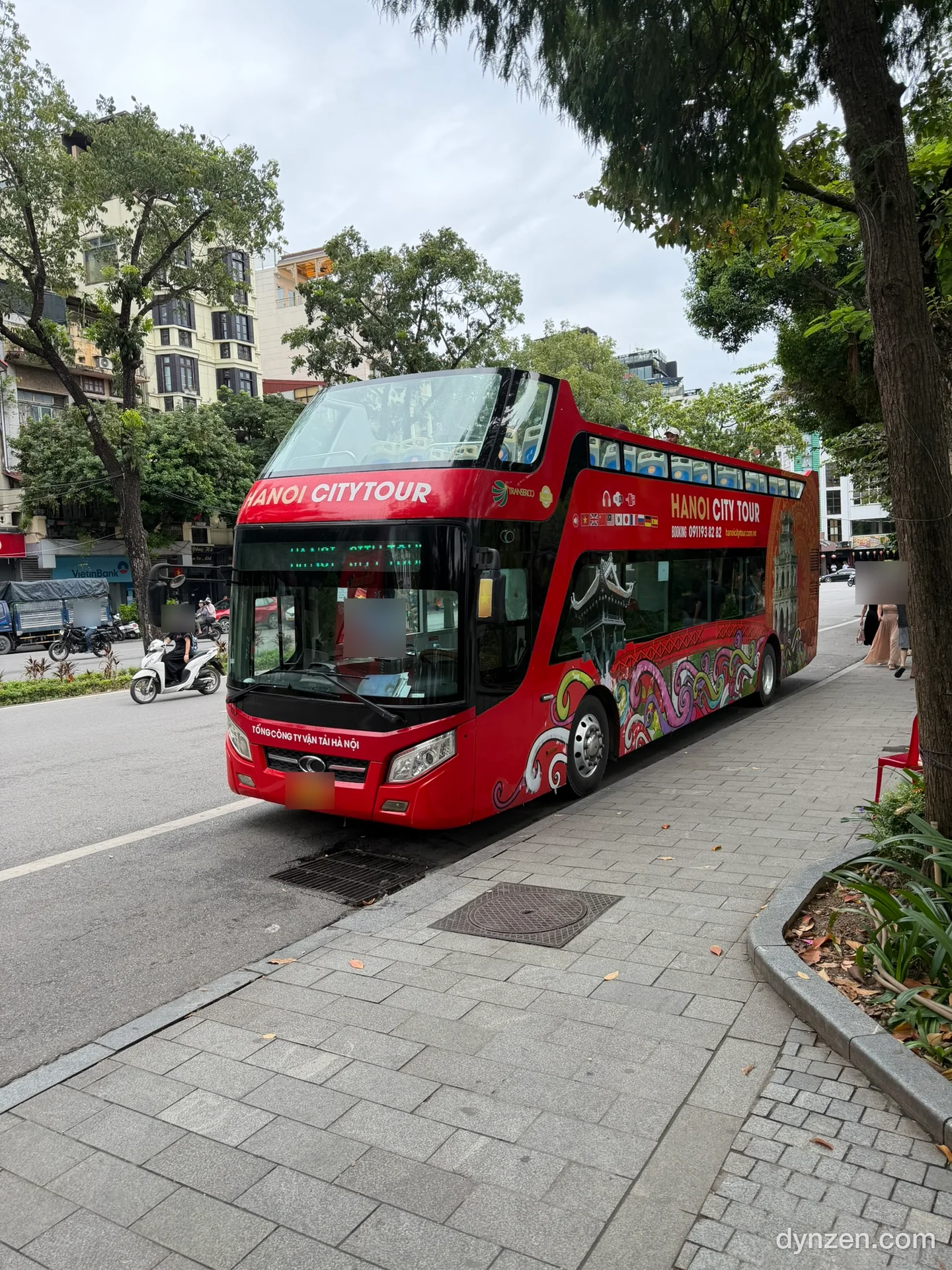 호안끼엠 거리에 선 빨간 2층 버스 HANOI CITY TOUR, 위층은 지붕 없이 열려 있고 측면에 용 그림이 그려져 있다