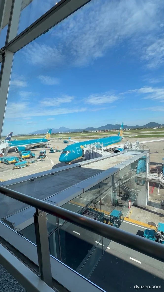 노이바이 국제공항 탑승교 너머로 보이는 베트남항공 여객기 여러 대, 맑은 하늘 아래 멀리 산이 보인다
