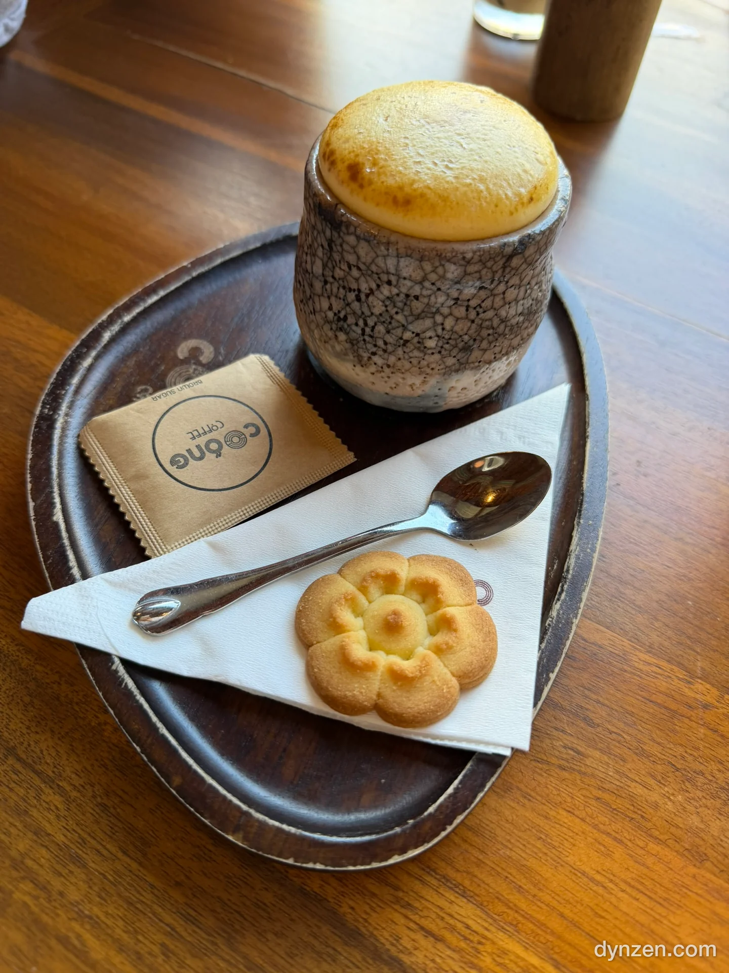 Coóng Coffee 에그 커피, 노릇하게 그을린 거품이 올라간 도자기 잔과 꽃모양 쿠키, ‘Coóng COFFEE’ 설탕 봉지