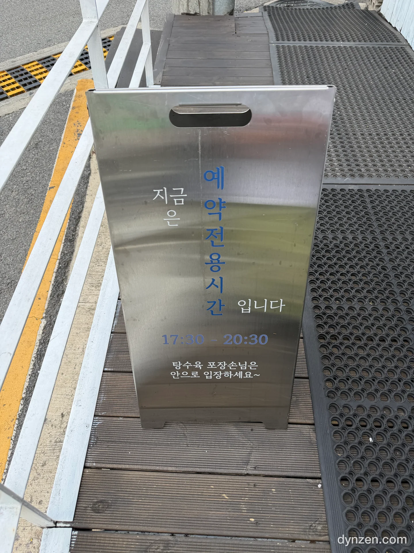 가게 앞 계단 위에 세워진 ‘예약전용시간 17:30–20:30’ 안내가 적힌 스테인리스 입간판